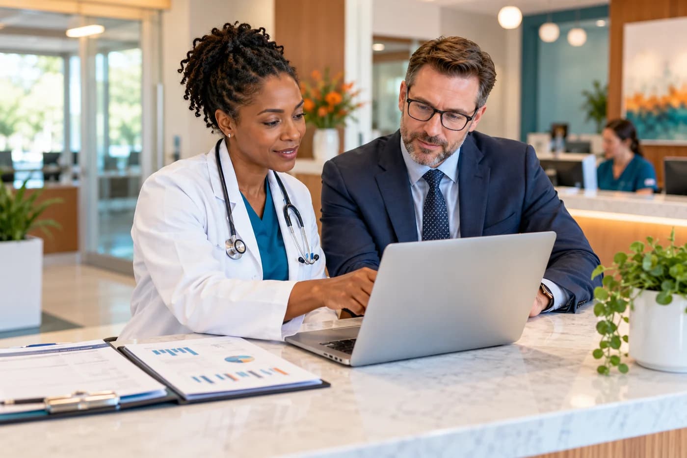 Illustrative physician and administrator reviewing a laptop in a medical practice