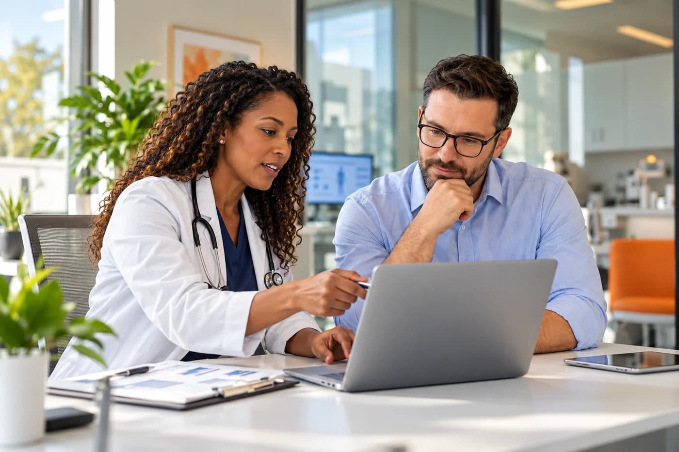 Illustrative scene of healthcare operations colleagues working through a process at a laptop.